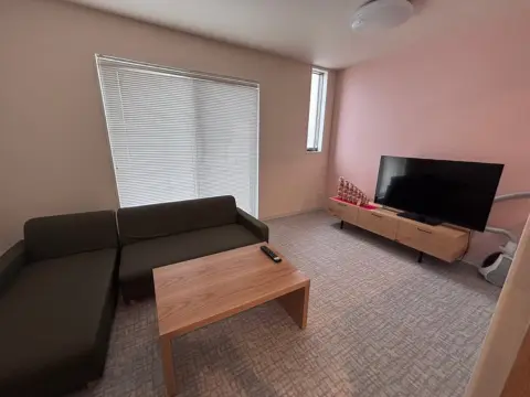 Ruang santai bersama asrama Oneness Court dengan sofa dan TV