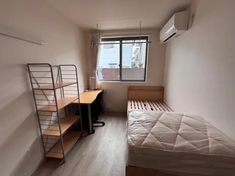Kamar pribadi siswa di asrama Oneness Court dengan tempat tidur, meja, dan AC